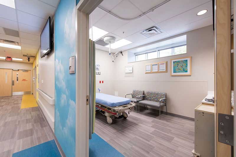 looking into a large hospital room with a bed and several chairs